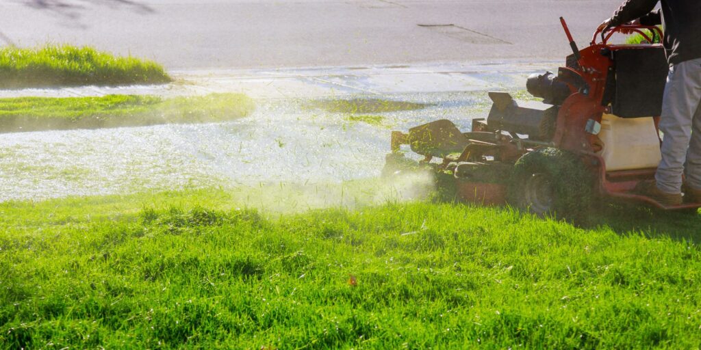 A man cutting wet grass on his lawn mower