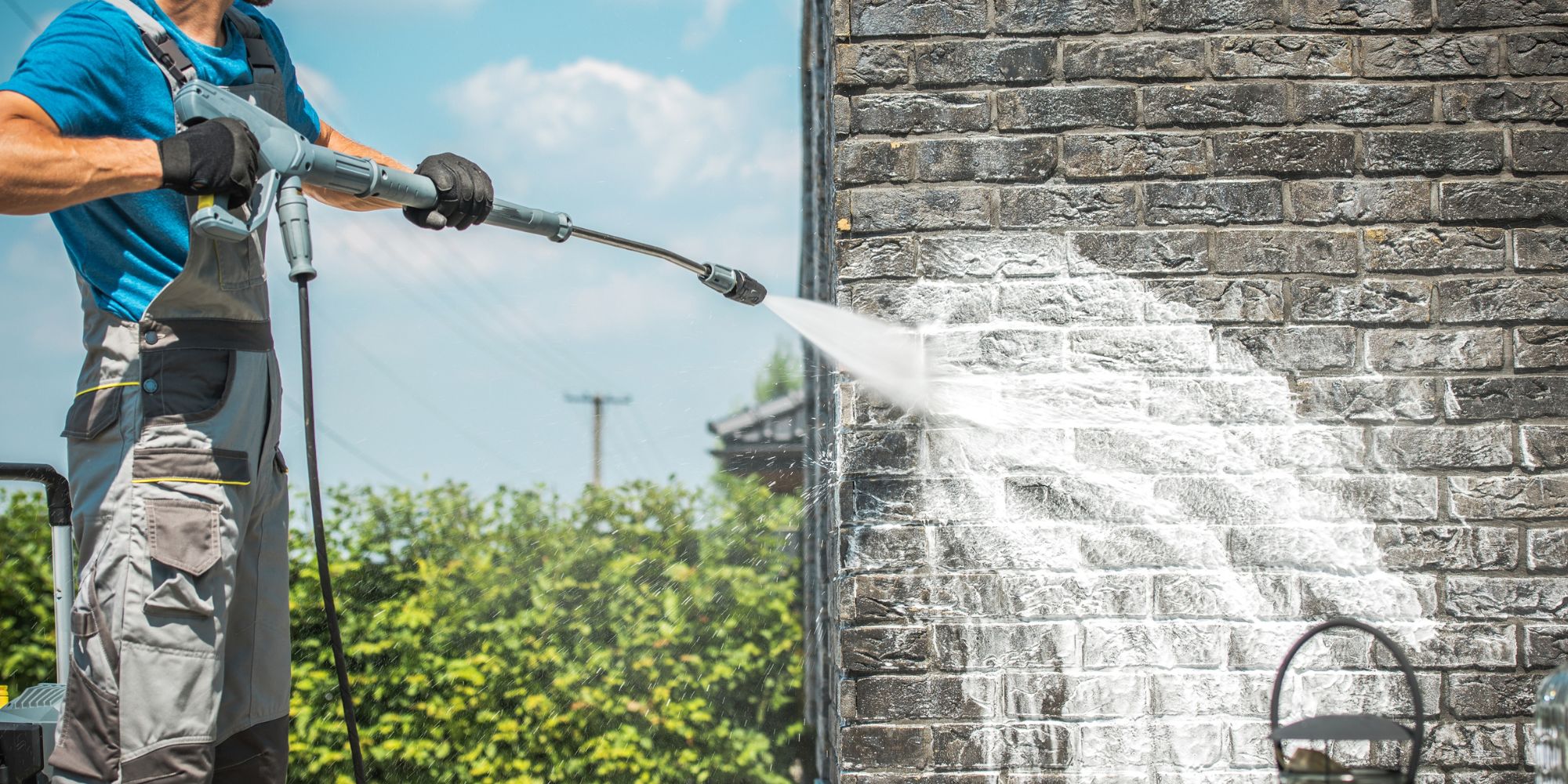 A man soft washing a brick house